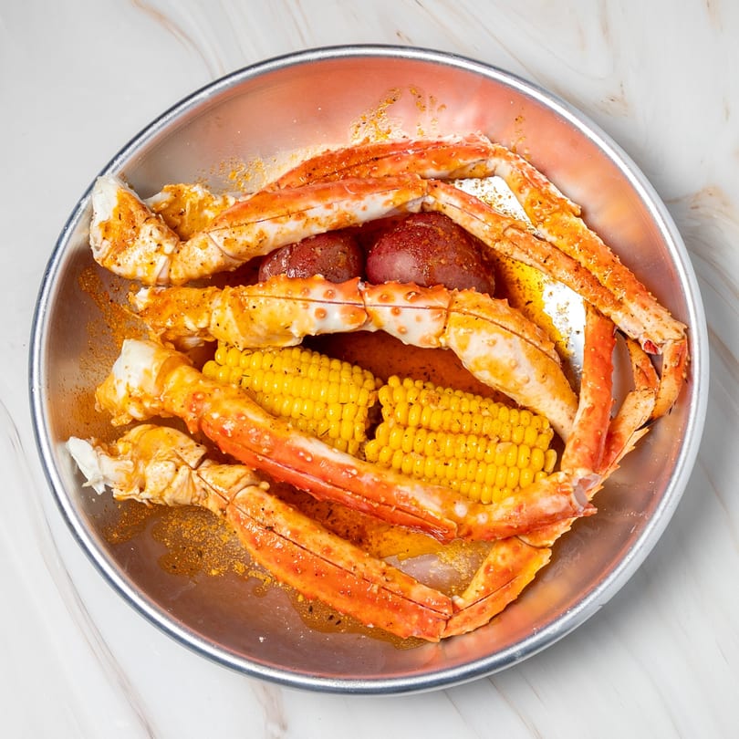 Shake Shake Seafood Monroe's crab legs, corn on the cob, and potatoes in a metal bowl.