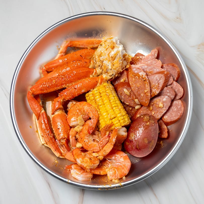 Shake Shake Seafood Monroe's seafood boil with crab legs, shrimp, corn, sausage, and potatoes in a metal bowl.